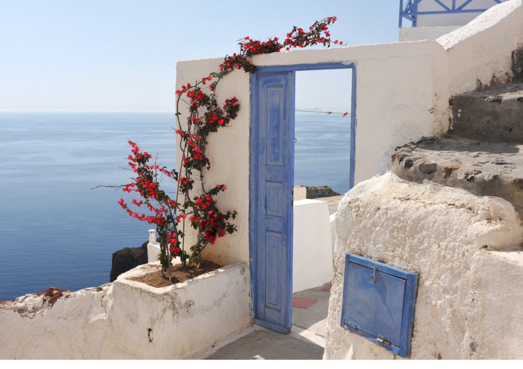 Traditional blue door with red bougainvillea flowers and sea view in Greece, inspiration for weddings and romantic private events by Sirtaki Events. הפקת אירועים ביוון