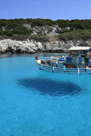 A small traditional boat in crystal-clear turquoise waters in Greece, boat rental and production of private and romantic events at sea by Sirtaki Events.
