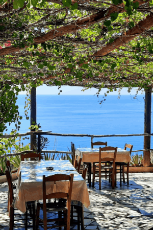 Table setting under a grape arbor overlooking the sea in Greece, inspiration for private events and outdoor weddings by Sirtaki Events.